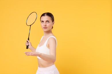 Young woman with badminton racket on orange background, space for text