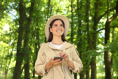 Photo of Forester with smartphone examining plants in forest