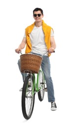 Smiling man in sunglasses riding bicycle with basket on white background