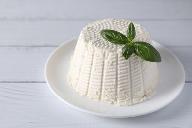 Fresh ricotta (cream cheese) and basil on white wooden table