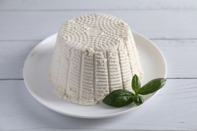 Fresh ricotta (cream cheese) and basil on white wooden table