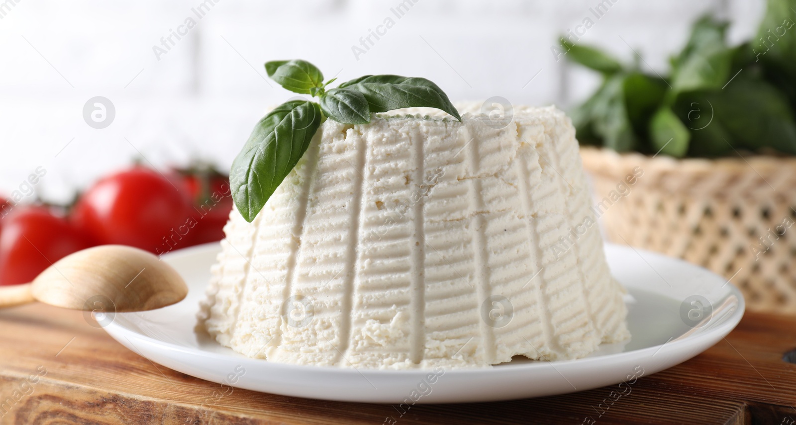 Photo of Fresh ricotta (cream cheese) with basil and spoon on table, closeup