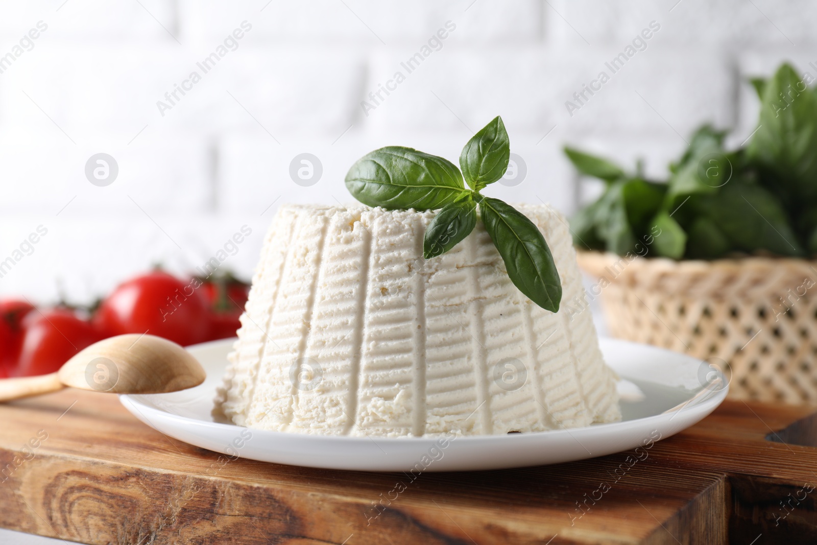 Photo of Fresh ricotta (cream cheese) with basil on table, closeup