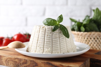 Fresh ricotta (cream cheese) with basil on table, closeup