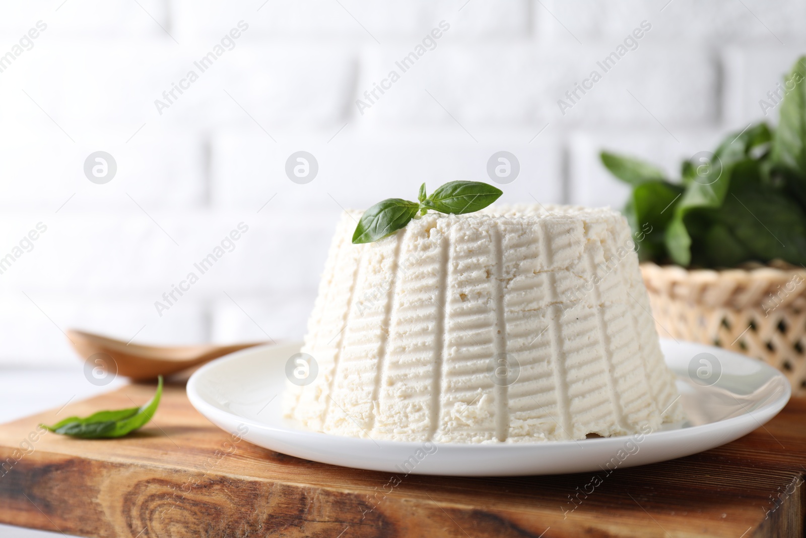 Photo of Fresh ricotta (cream cheese) with basil on table