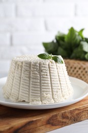 Fresh ricotta (cream cheese) with basil on white table