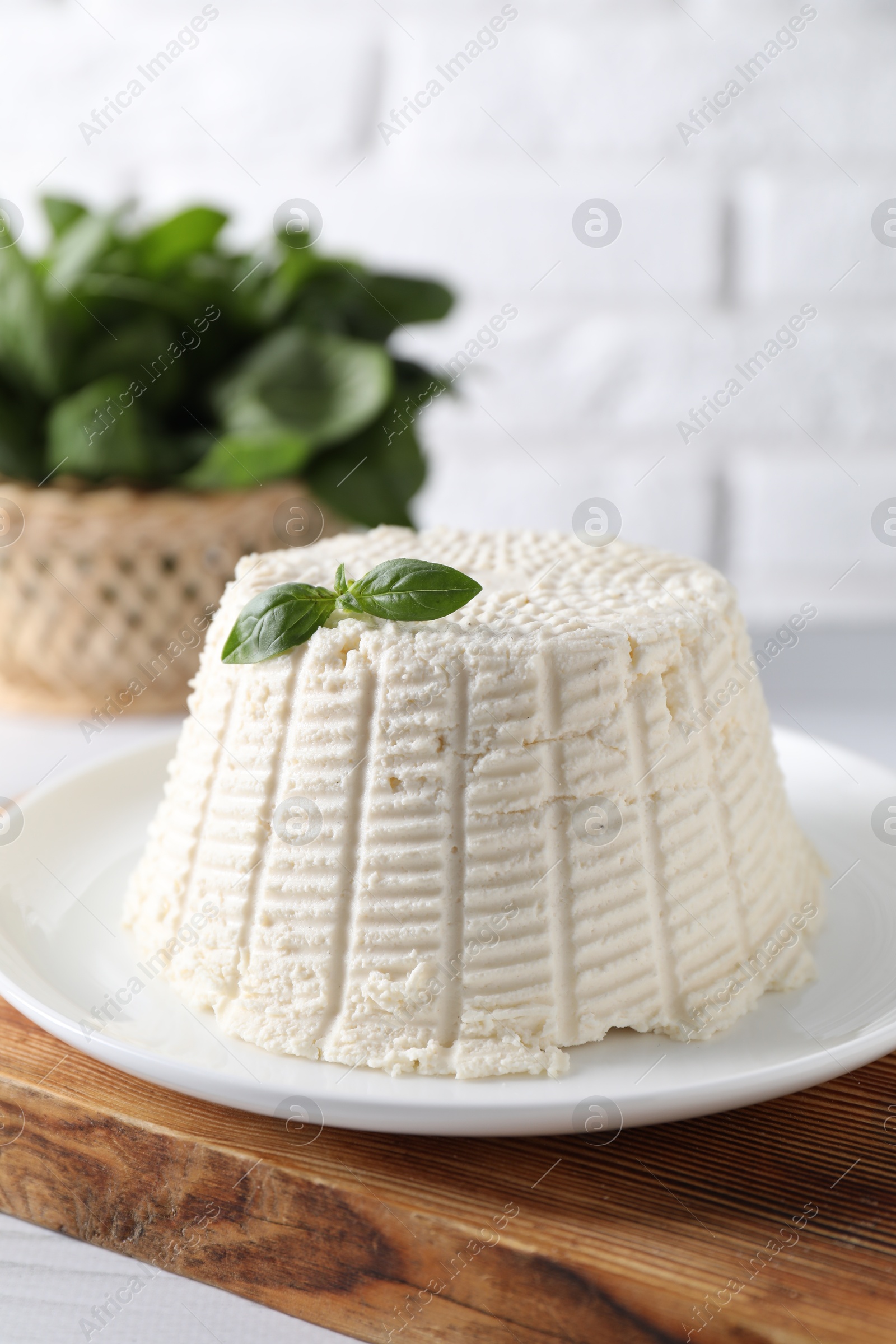 Photo of Fresh ricotta (cream cheese) with basil on white table