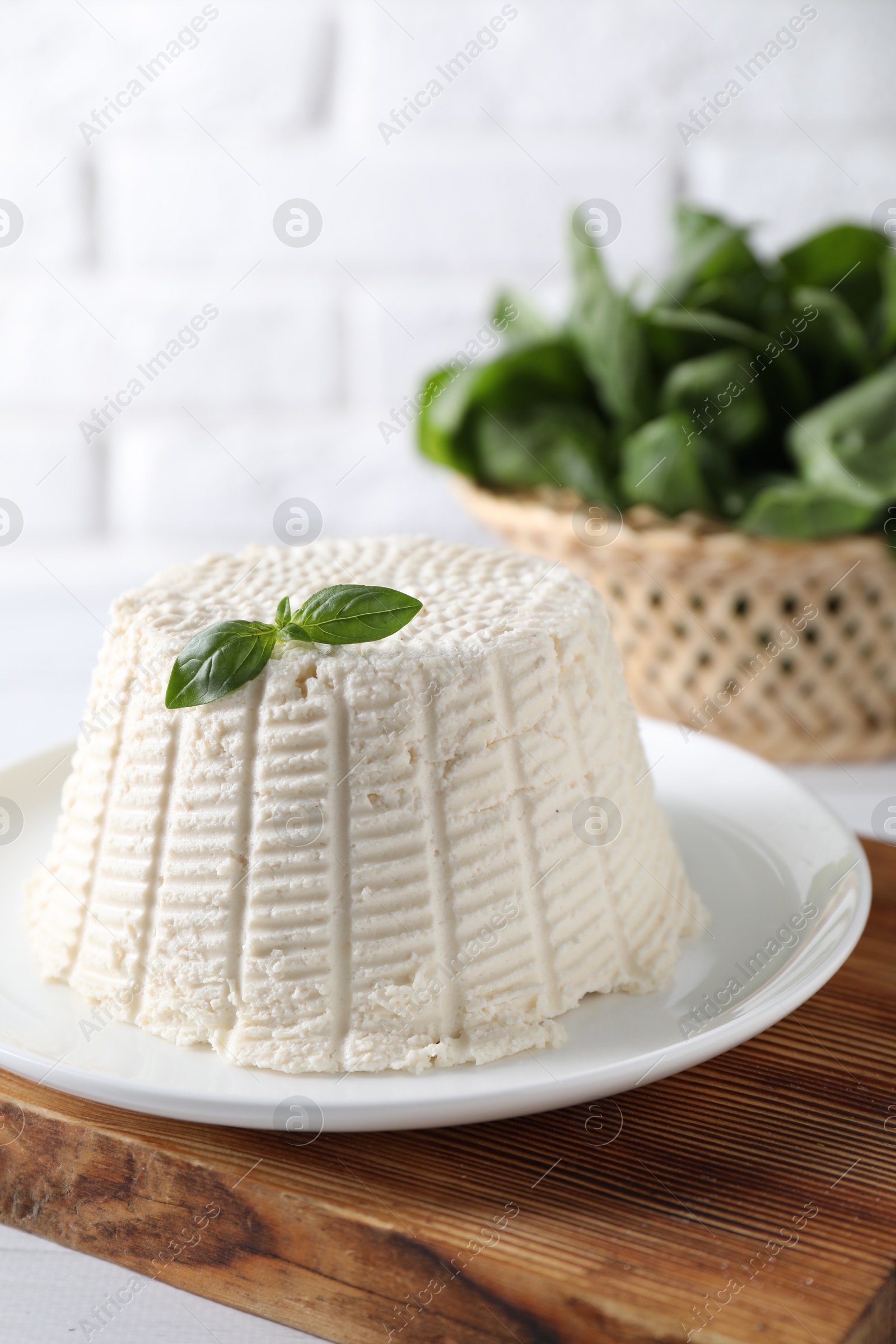 Photo of Fresh ricotta (cream cheese) with basil on white table