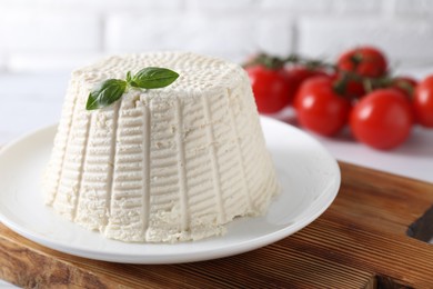 Photo of Fresh ricotta (cream cheese) with basil on white table, closeup