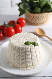 Fresh ricotta (cream cheese) with basil on white wooden table