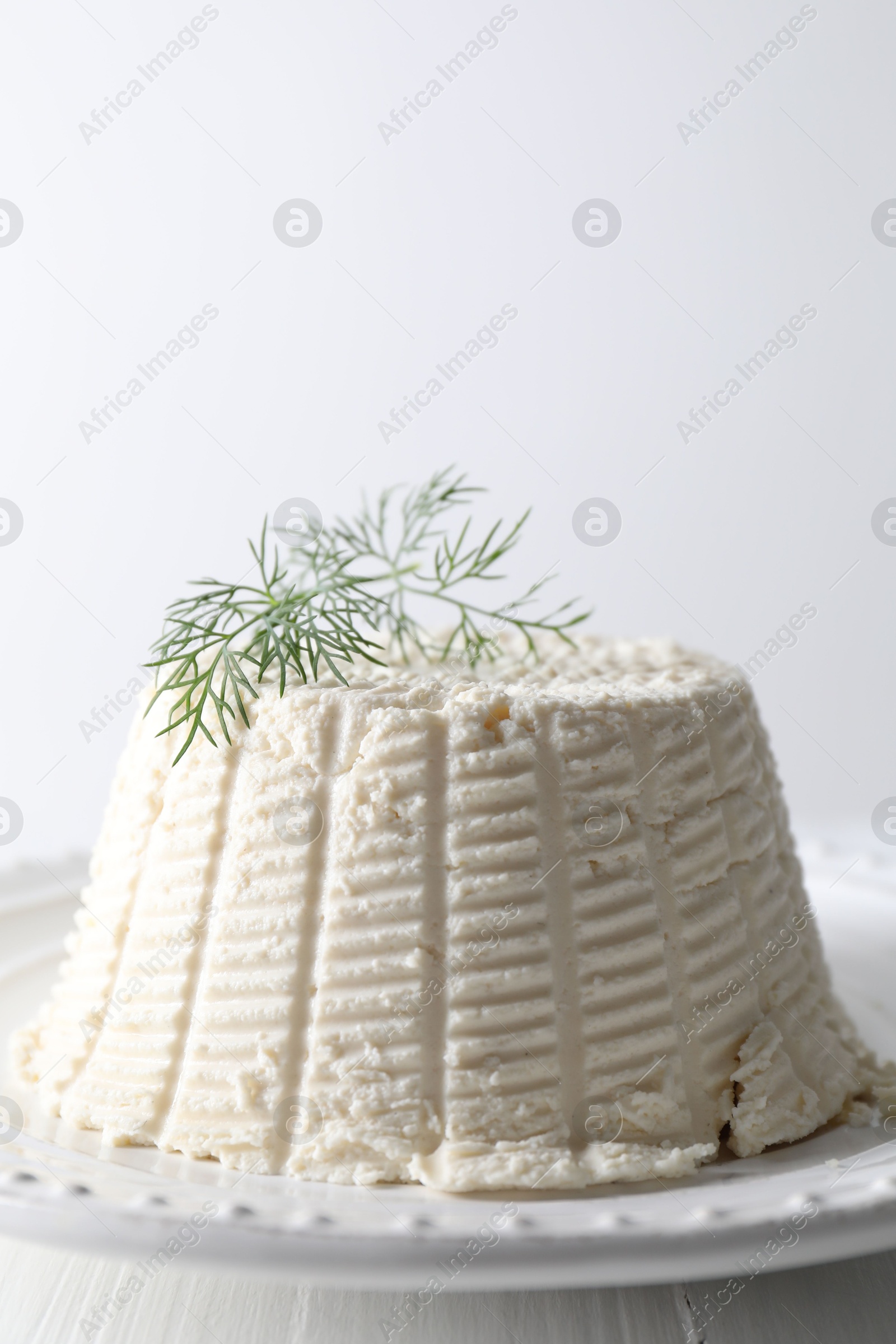 Photo of Fresh ricotta (cream cheese) with dill on white table, closeup