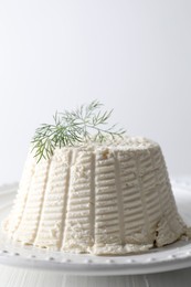 Photo of Fresh ricotta (cream cheese) with dill on white table, closeup