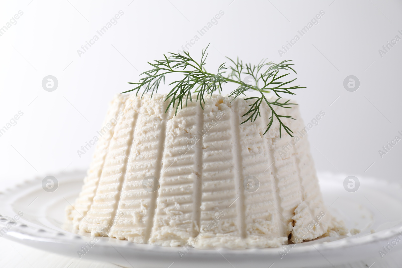 Photo of Fresh ricotta (cream cheese) with dill on white table, closeup