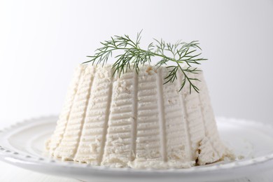 Photo of Fresh ricotta (cream cheese) with dill on white table, closeup