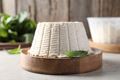 Photo of Fresh ricotta (cream cheese) and basil on light grey table, closeup