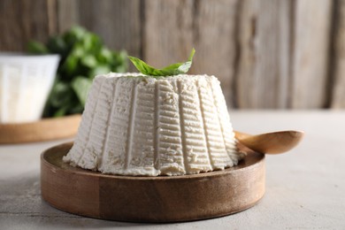 Photo of Fresh ricotta (cream cheese) and basil on light grey table, closeup