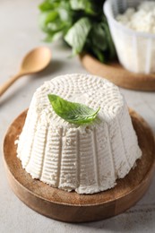 Fresh ricotta (cream cheese) and basil on light grey table, closeup