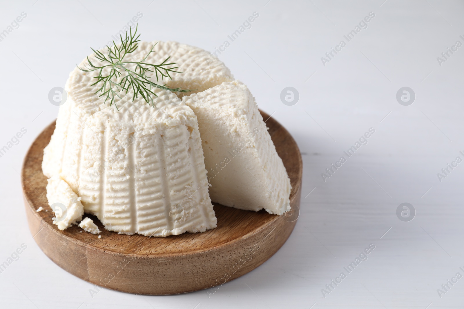 Photo of Fresh cut ricotta (cream cheese) with dill on white wooden table. Space for text