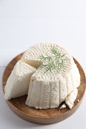 Photo of Fresh cut ricotta (cream cheese) with dill on white table