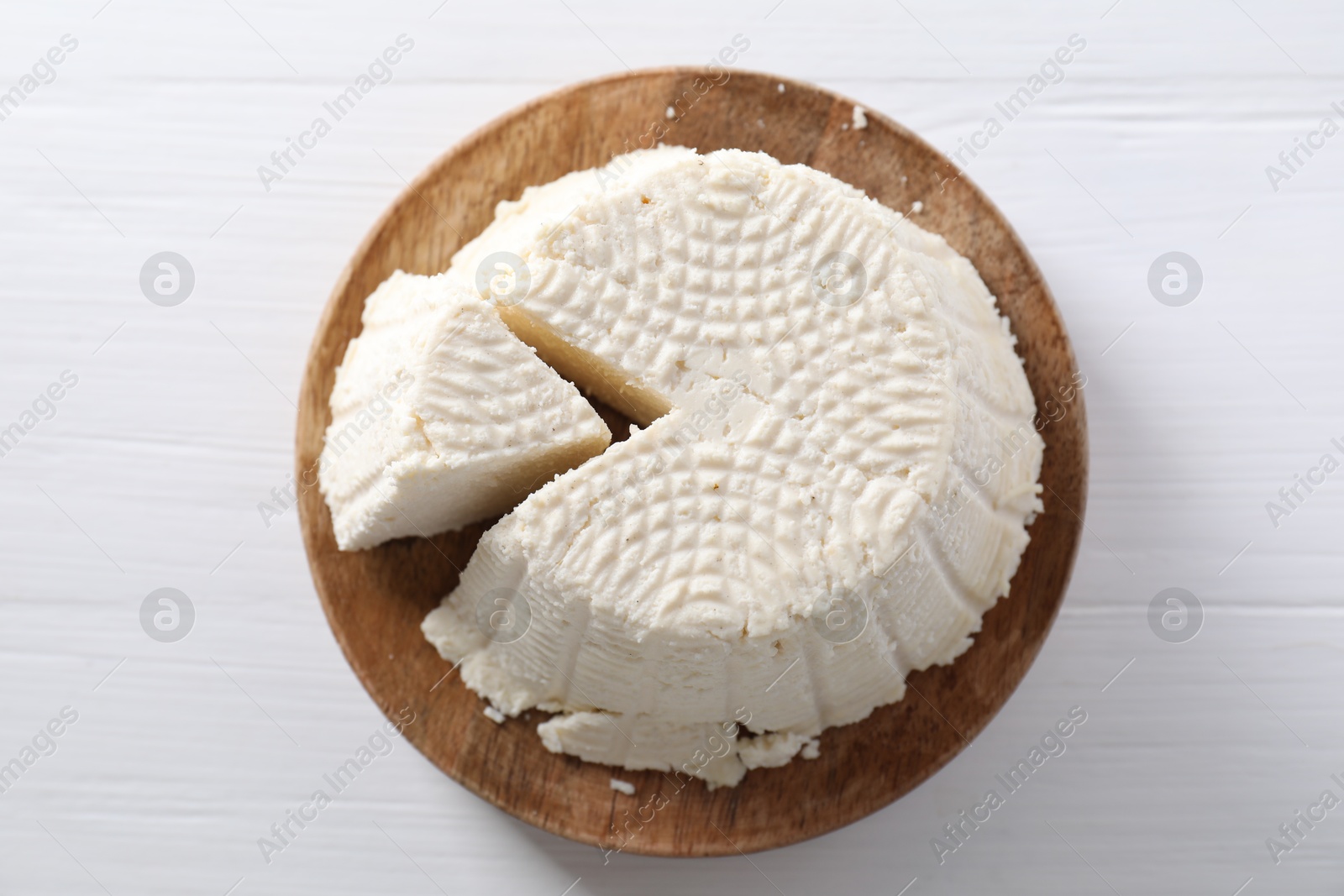 Photo of Fresh cut ricotta (cream cheese) on white wooden table, top view