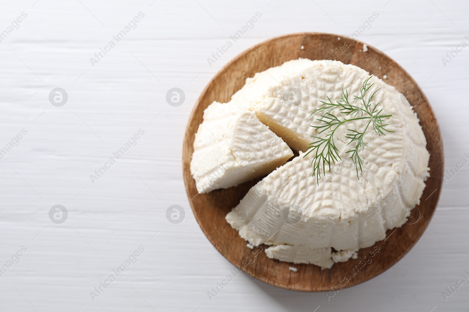 Photo of Fresh cut ricotta (cream cheese) with dill on white wooden table, top view. Space for text