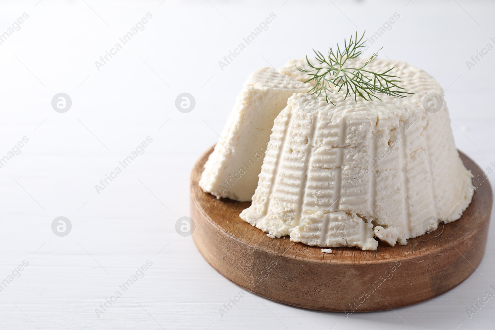 Photo of Fresh cut ricotta (cream cheese) with dill on white wooden table. Space for text