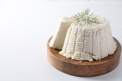 Fresh cut ricotta (cream cheese) with dill on white wooden table. Space for text