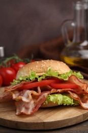 Delicious burger with bacon, tomato and lettuce on table