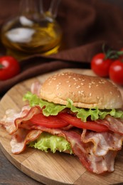Photo of Delicious burger with bacon, tomato and lettuce on table