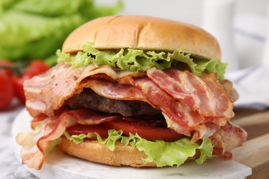 Photo of Delicious burger with bacon, patty and tomato on table