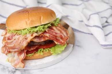 Photo of Delicious burger with bacon, patty and tomato on white marble table. Space for text