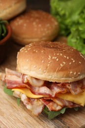 Photo of Delicious burger with bacon and cheese on table