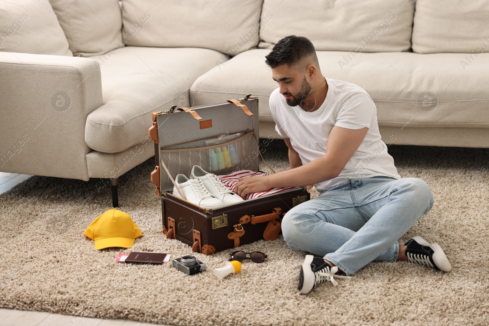 Photo of Man packing suitcase on floor at home