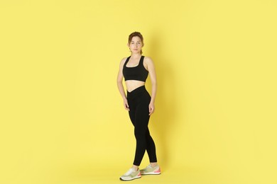 Photo of Woman with slim body posing on yellow background