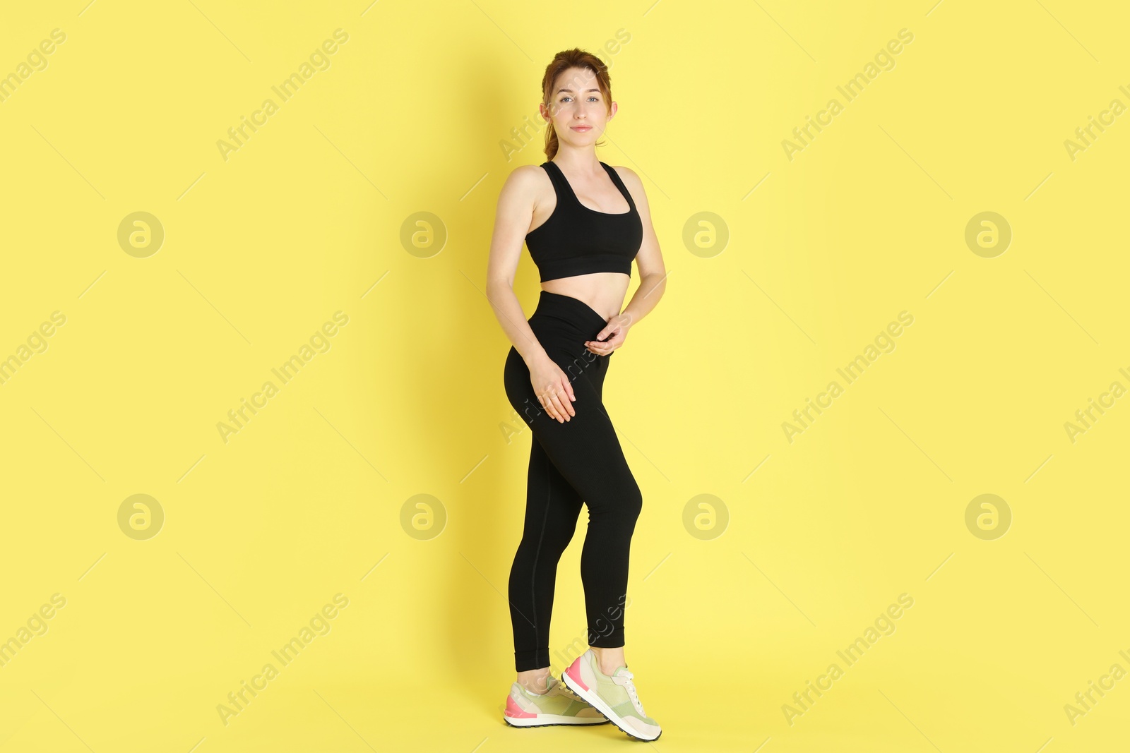 Photo of Woman with slim body posing on yellow background