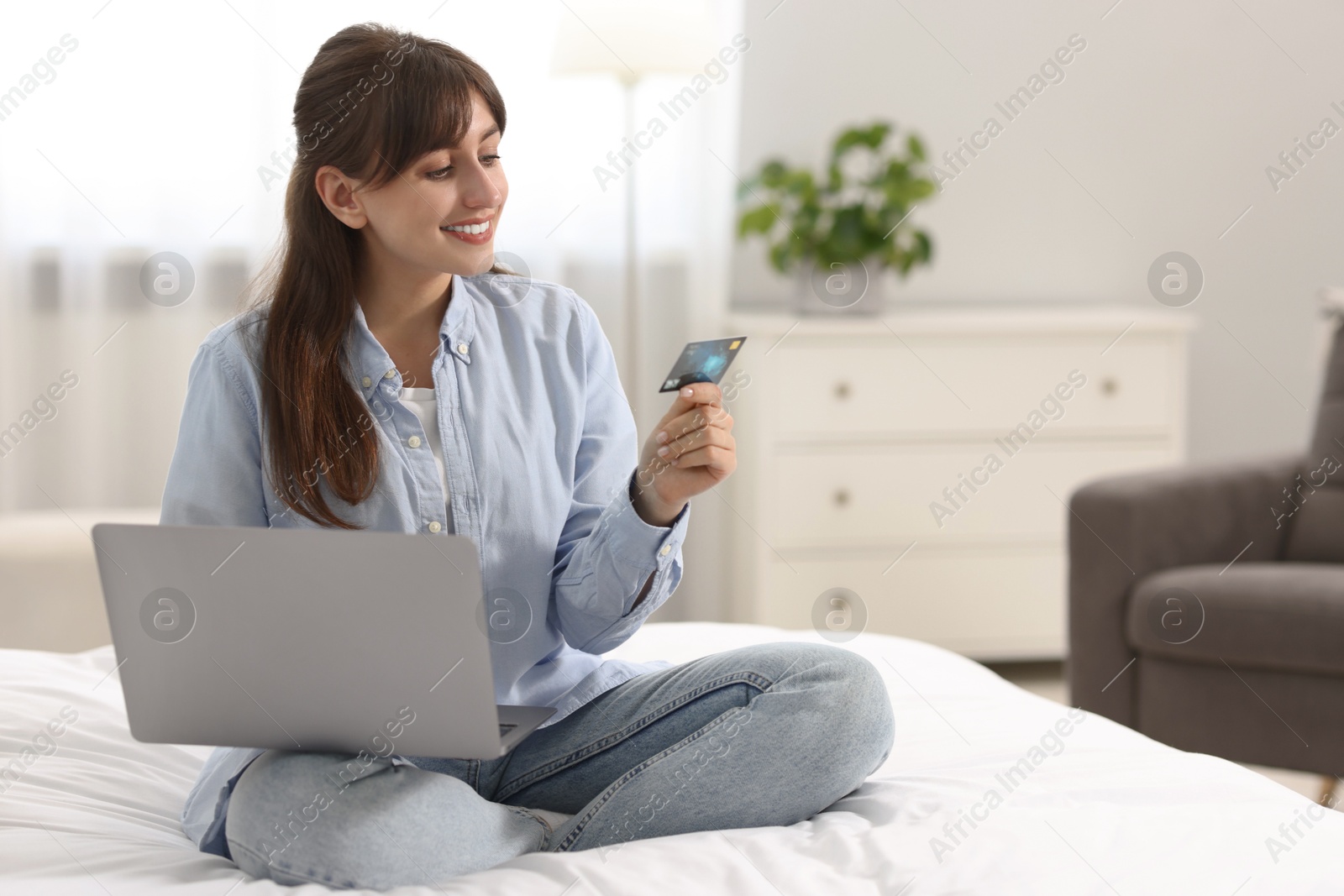 Photo of Online banking. Smiling woman with credit card and laptop paying purchase at home. Space for text