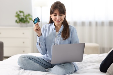 Online banking. Smiling woman with credit card and laptop paying purchase at home