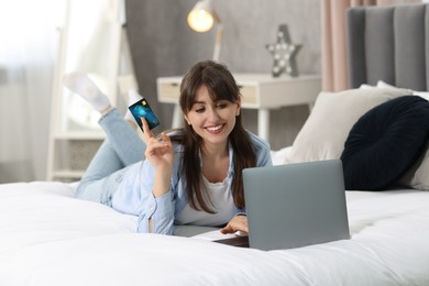 Photo of Online banking. Smiling woman with credit card and laptop paying purchase at home