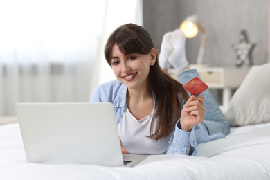 Photo of Online banking. Smiling woman with credit card and laptop paying purchase at home