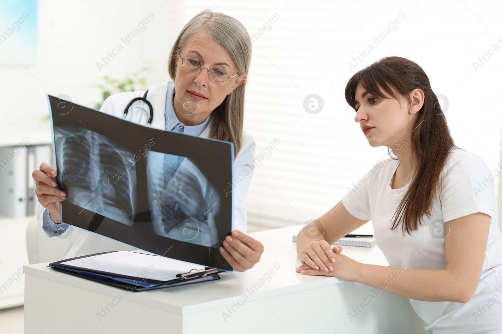 Photo of Lung disease. Doctor showing chest x-ray to her patient in clinic