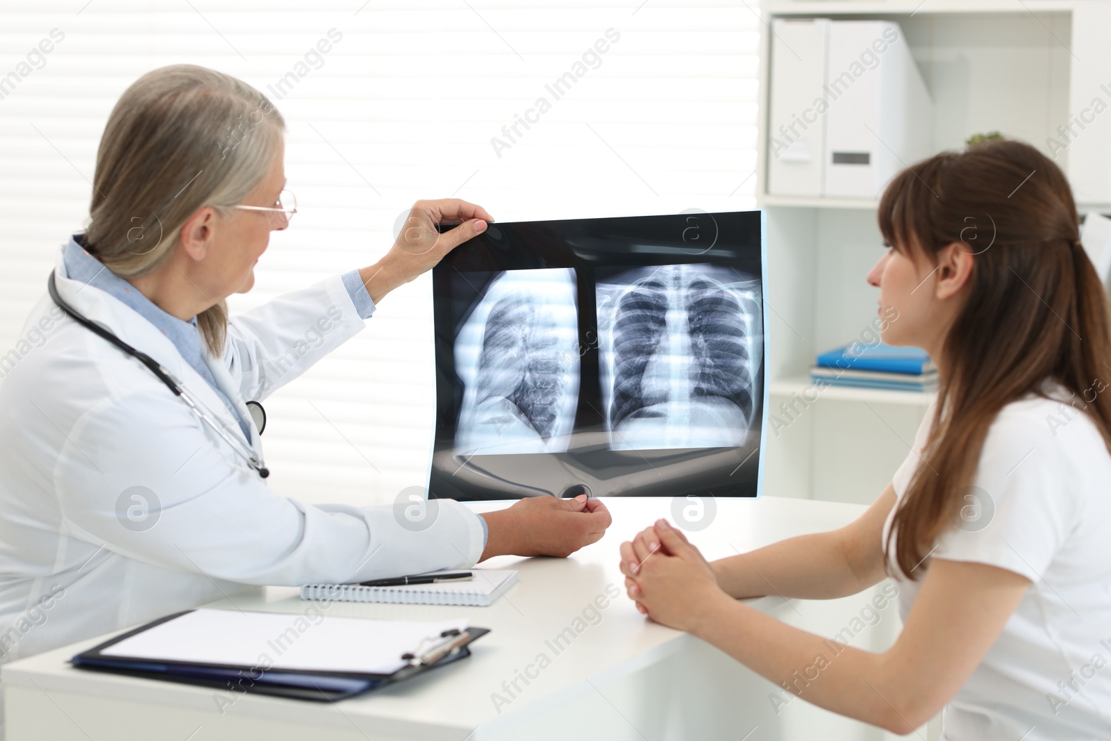 Photo of Lung disease. Doctor showing chest x-ray to her patient in clinic