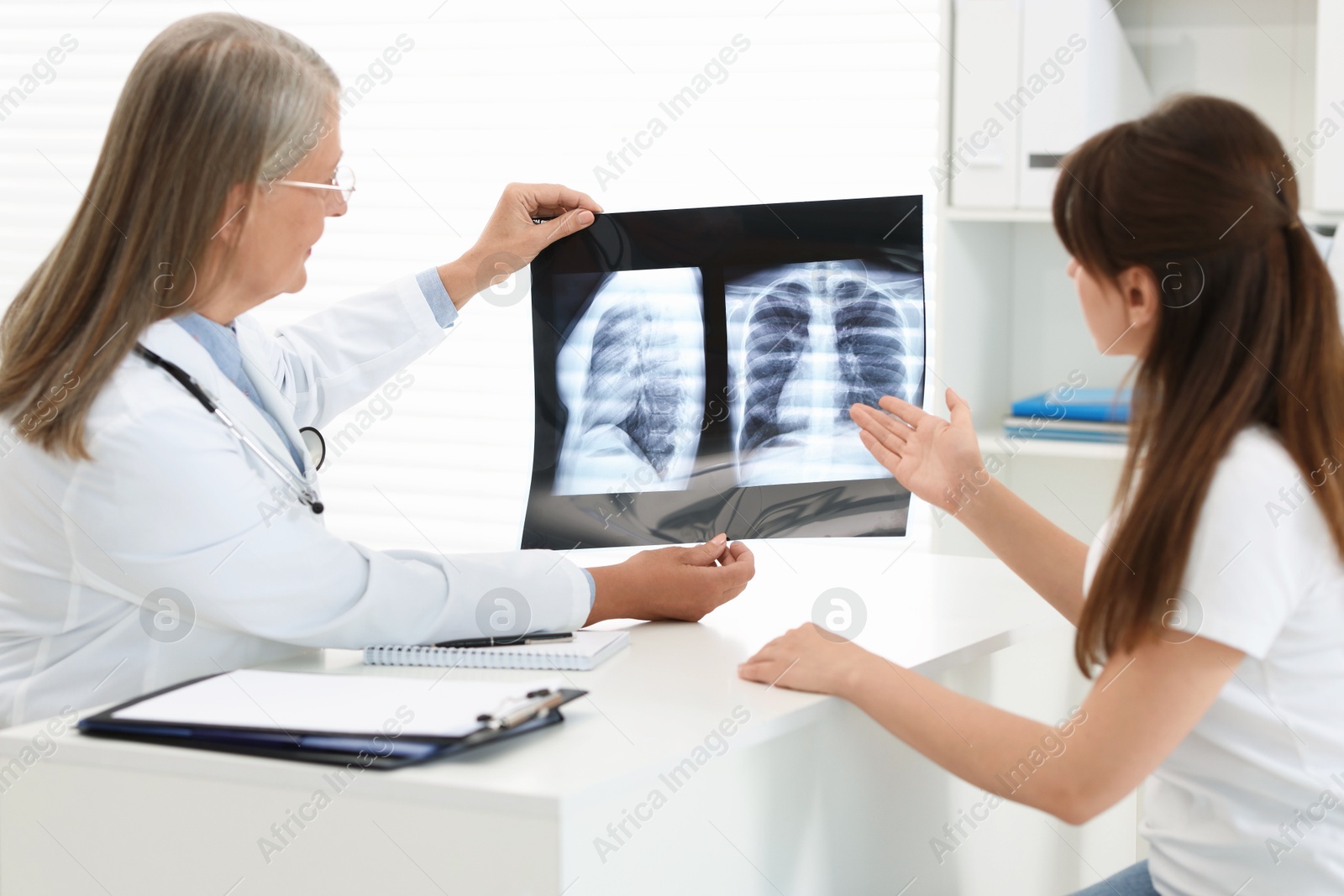 Photo of Lung disease. Doctor showing chest x-ray to her patient in clinic