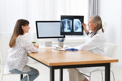 Lung disease. Doctor showing chest x-ray to her patient in clinic