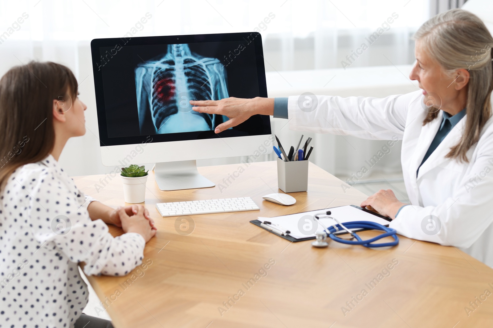 Photo of Lung cancer. Doctor showing chest x-ray to her patient in clinic