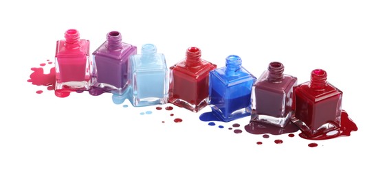 Photo of Many bottles and drops of colorful nail polishes isolated on white