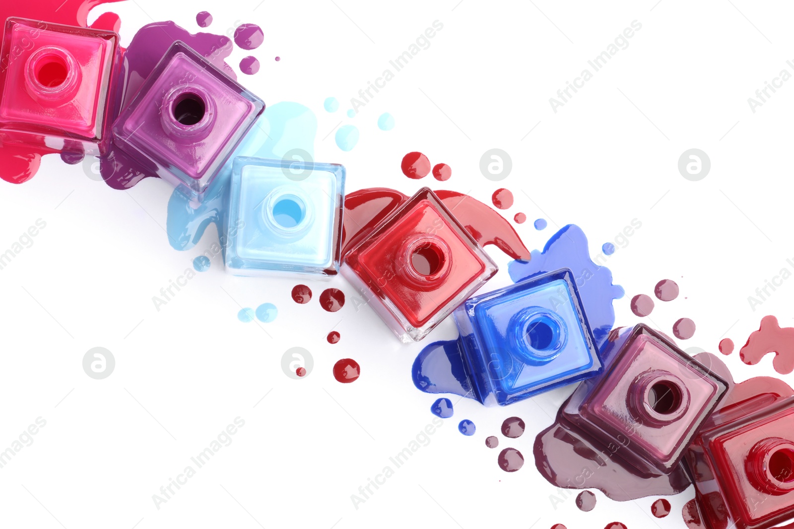 Photo of Many bottles and drops of colorful nail polishes isolated on white, top view