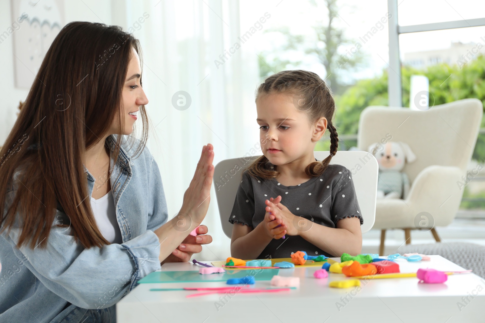 Photo of Play dough activity. Smiling mother with her daughter at table indoors