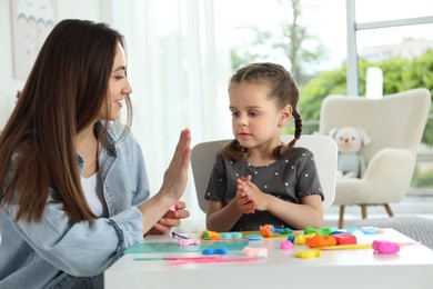 Play dough activity. Smiling mother with her daughter at table indoors