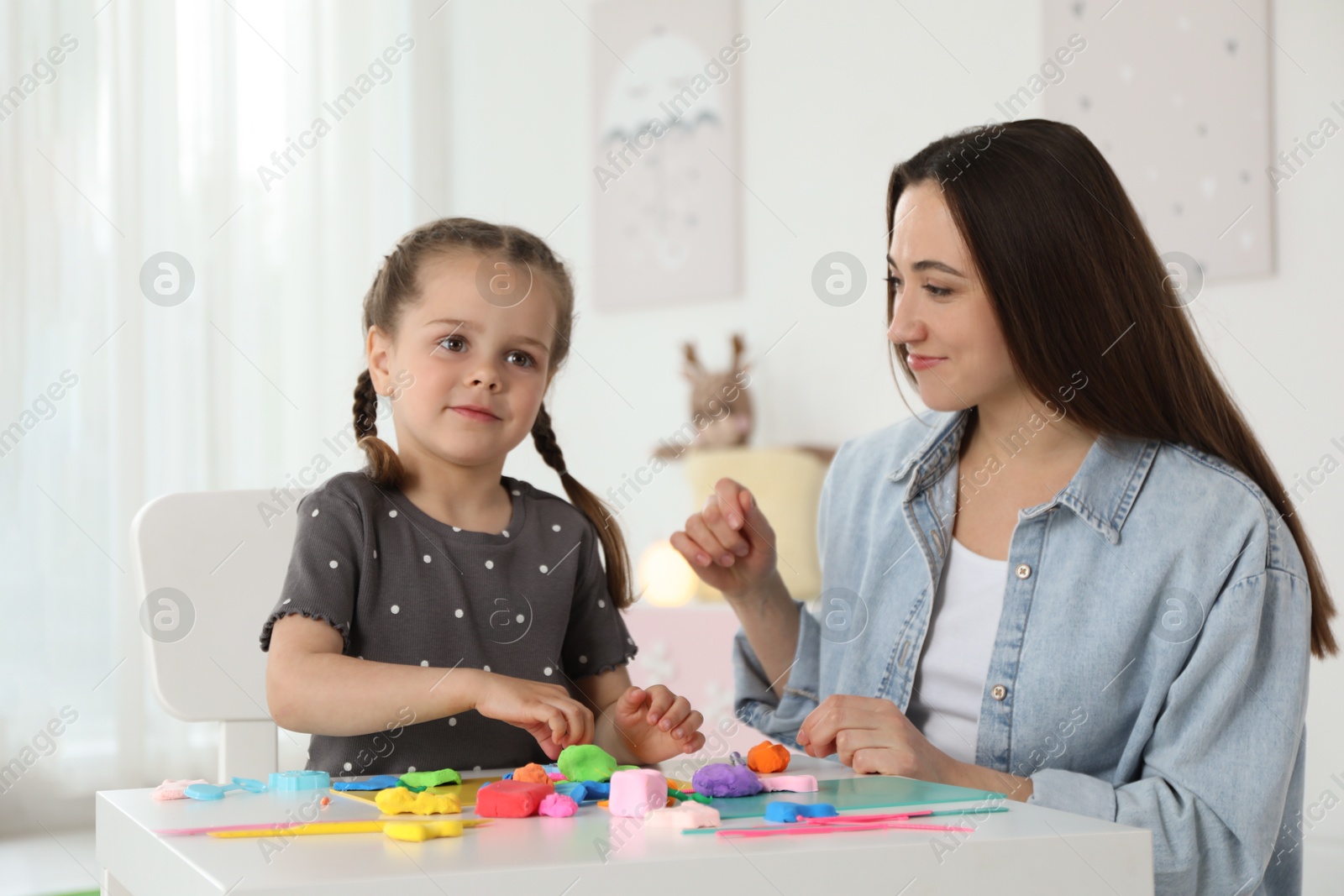 Photo of Play dough activity. Mother with her daughter at table indoors