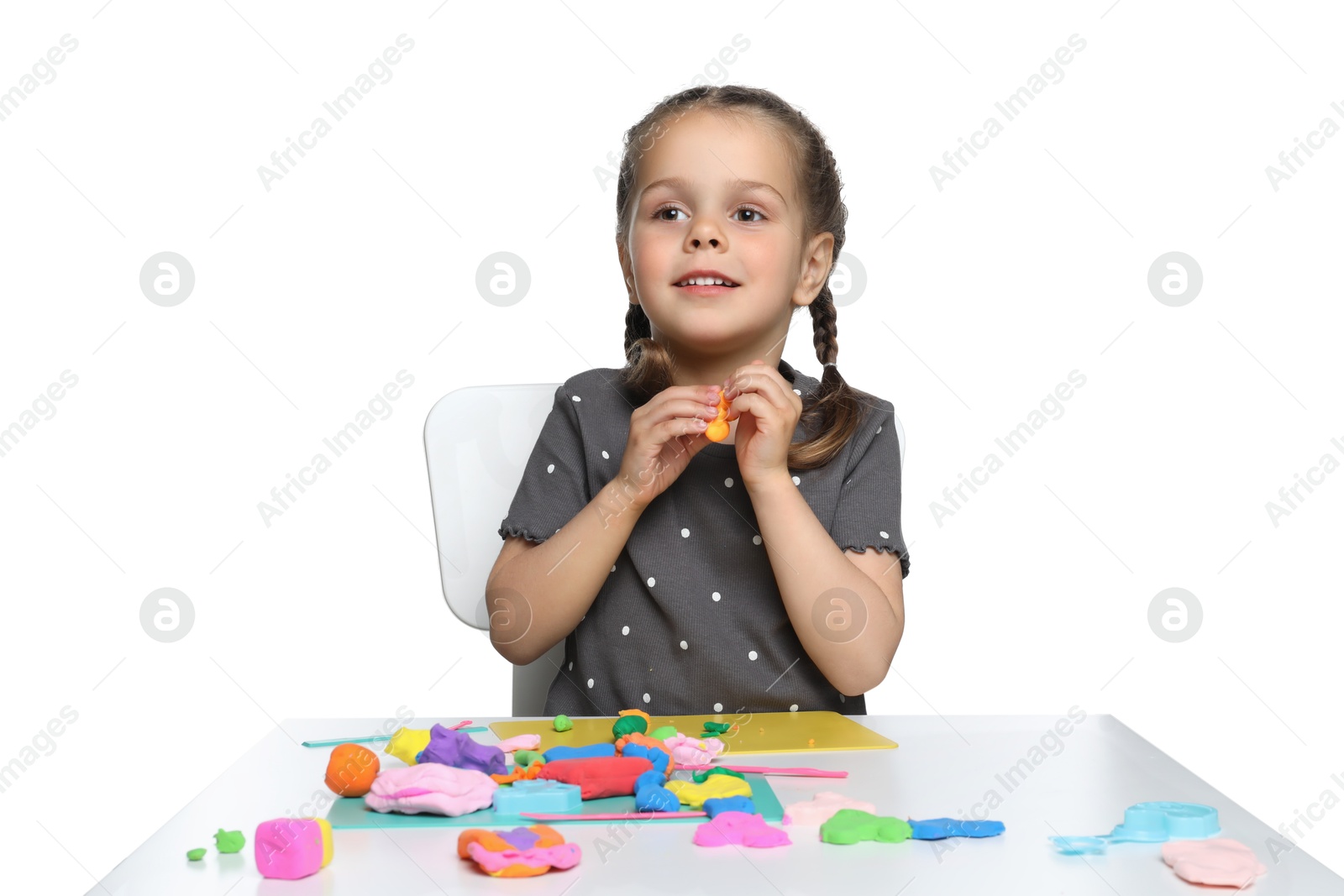 Photo of Little girl sculpting with play dough at table on white background